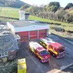 Fire engine and compact fire engine in front of fire station with countryside in background