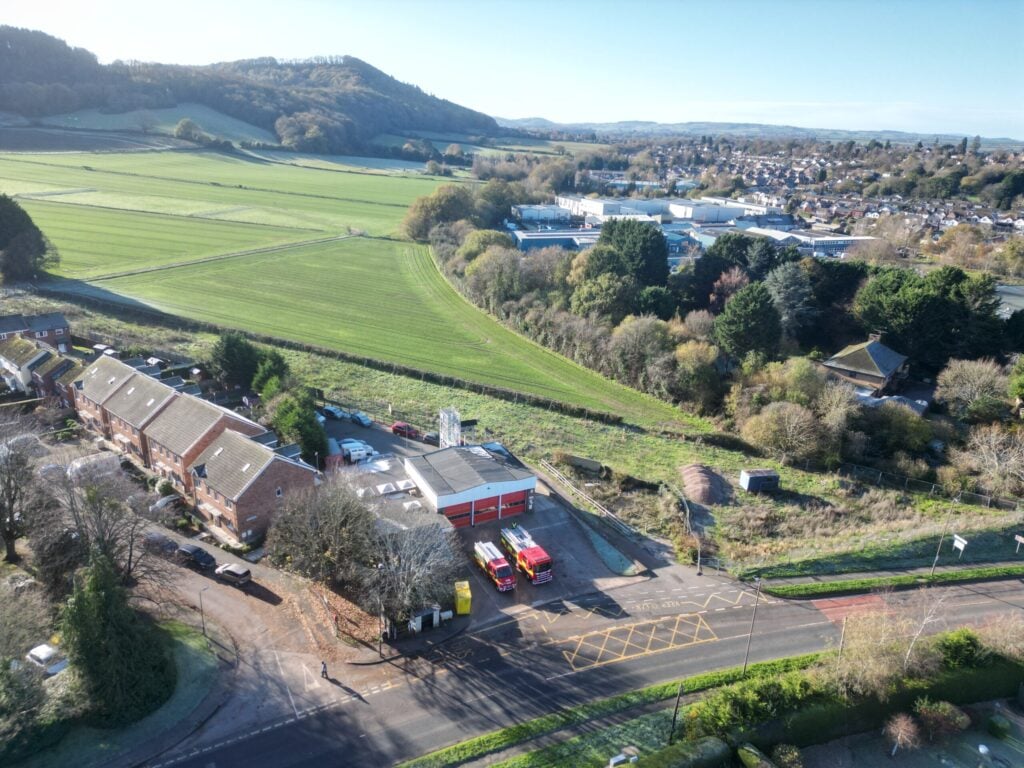 Fire engine and compact fire engine drone shot in front of fire station with countryside in background