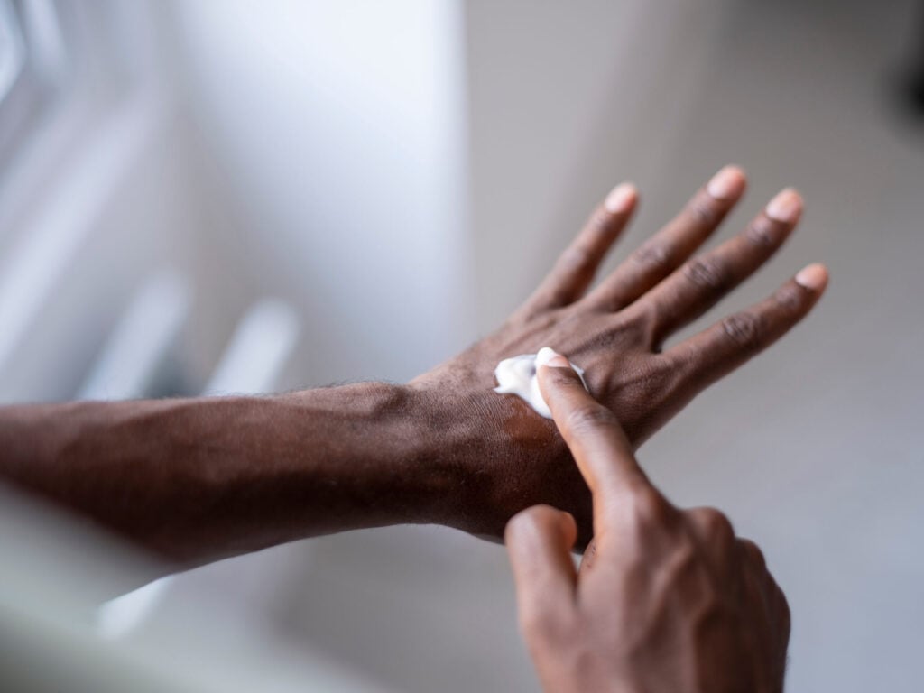 Close-up of person applying moisturiser on hand